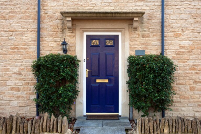 Modern blue painted front door flanked by shrubs